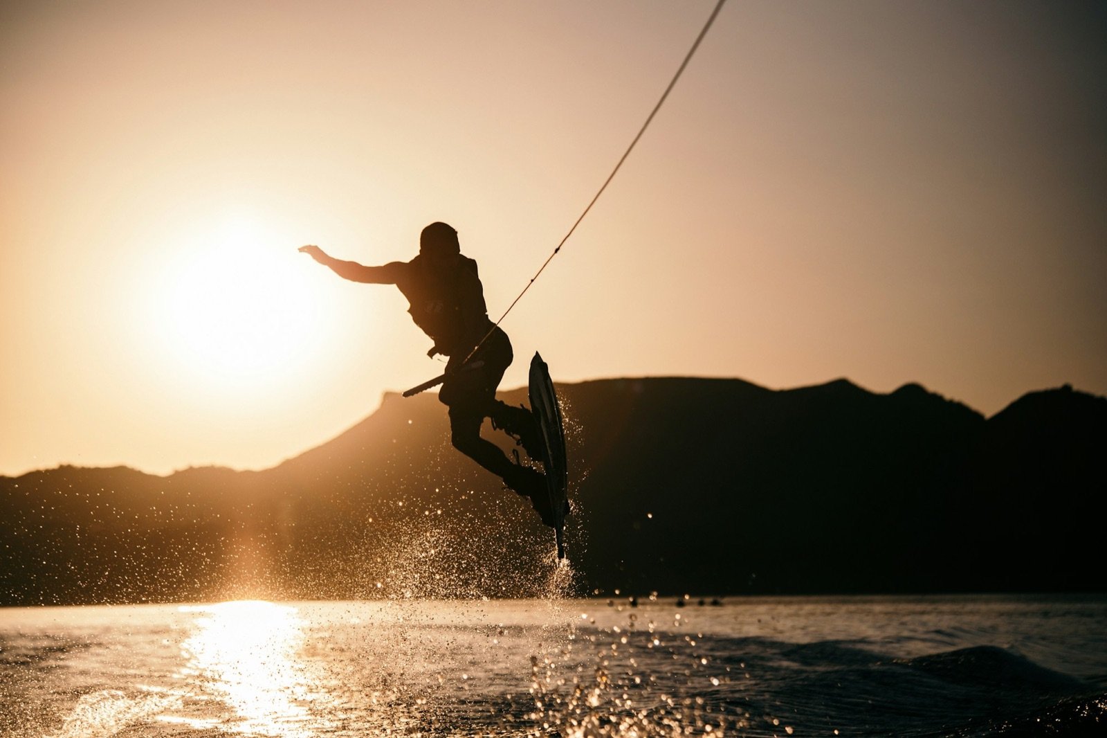 Wakeboarder catching air behind the boat at sunset